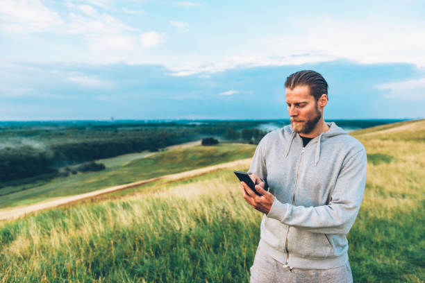 istock Hipster with beard uses smart phone outside in the country side 671568642