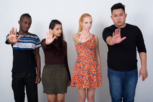 Studio shot of diverse group of multi ethnic friends showing stop hand sign together horizontal shot