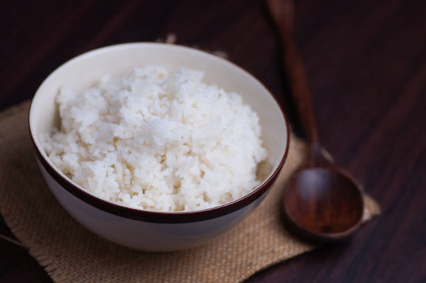 istock Thai rice in bowl with wooden spoon on table 671571156