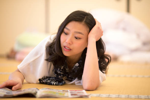 若い女性前面に横になっていると日本の畳部屋で雑誌を読んで