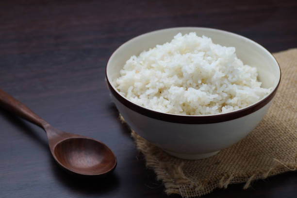 istock Thai rice in bowl with wooden spoon on table  in dark tone 671582746