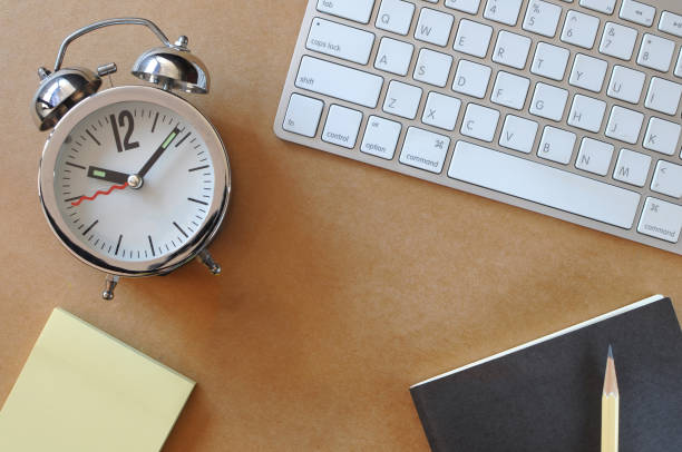 istock Working desk with alarm clock, keyboard, sticky note, book and pencil 671583366