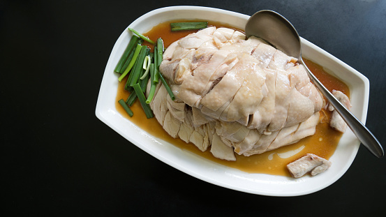Hainanese chicken chop the favorite food in Singapore with white dish over black background with copy space. Asian favorite food concept. Chicken only no rice.
