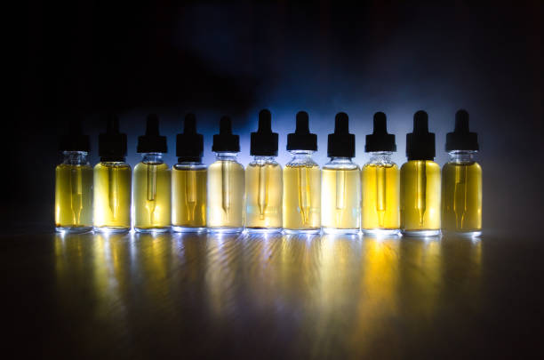 istock Vape concept. Smoke clouds and vape liquid bottles on dark background. Light effects. 671601514