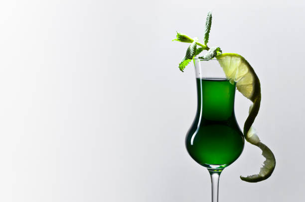 Glass of absinthe garnished with a slice of lime and mint leaves . Copy space .