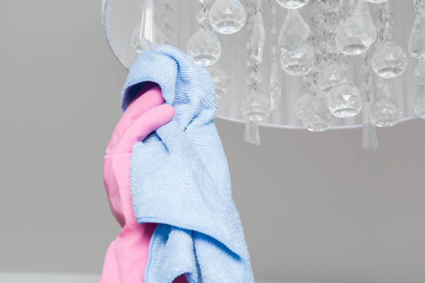 istock Hand in pink protective glove with rag cleaning chandelier. Early spring cleaning or regular clean up. Maid cleans house. 671618966