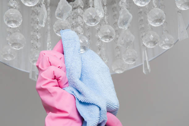 istock Hand in pink protective glove with rag cleaning chandelier. Early spring cleaning or regular clean up. Maid cleans house. 671619002