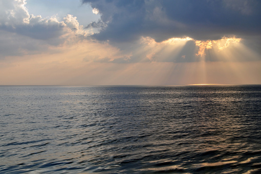 The sun's rays through the clouds above the sea.
