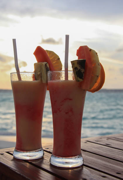Two coctails on the wooden table on the sunset background