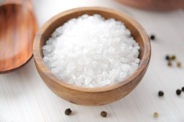 istock Sea salt in wooden bowl on white table 671655196