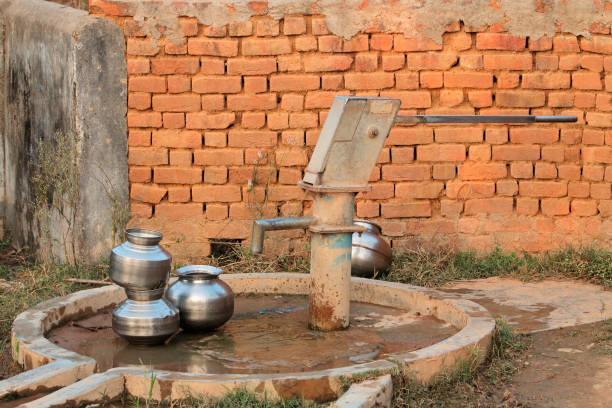 Old hand operated water pump and water containers in rural India