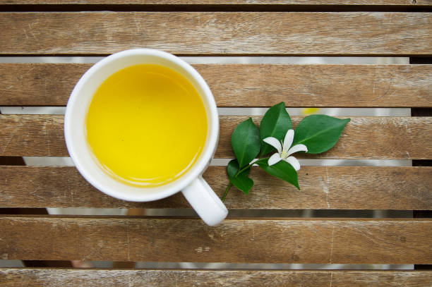 una tazza di tè con foglia verde e fiore bianco su tavolo di legno - murraya paniculata foto e immagini stock