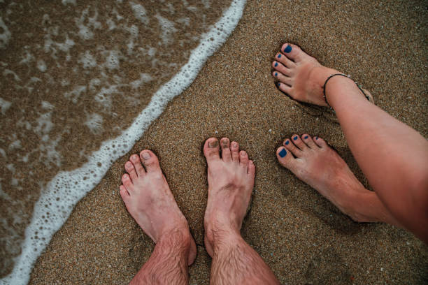 istock Man and woman legs on a beach in a surf 671682976