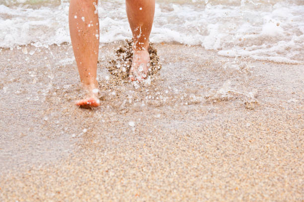 istock feet of boy walking along the beach 671685412