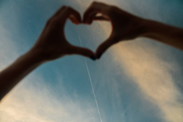 Silhouette hand in heart shape with beautiful sunset sky and Airplane background. Focus on the Background.