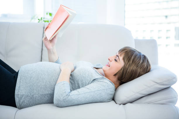 istock Happy woman reading book at home 671689984