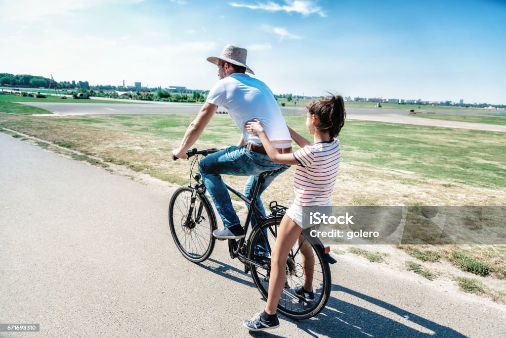 Vater auf Fahrrad mit Teenager-Tochter auf dem Träger - Lizenzfrei Berlin Stock-Foto