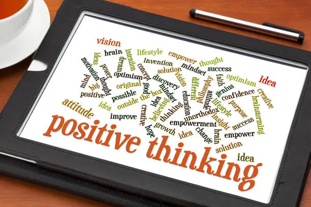 positive thinking and attitude word cloud on a digital tablet with a cup of tea
