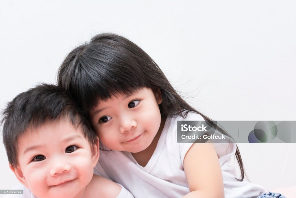 Baby Sister and Brother in White shirt Hugging each other. Baby - Human Age Stock Photo