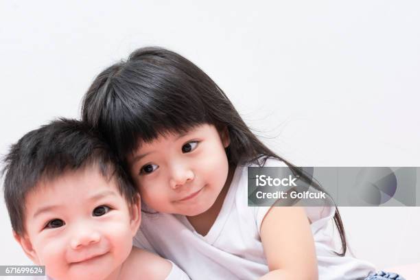 Baby Sister And Brother In White Shirt Hugging Each Other Stock Photo - Download Image Now