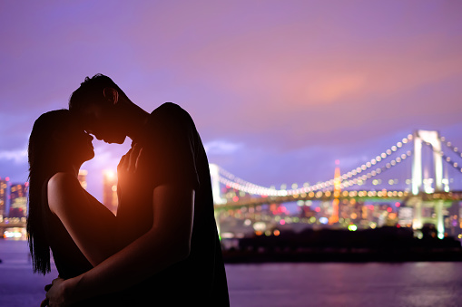 silhouette of romantic lovers with Odaiba in tokyo with sunset