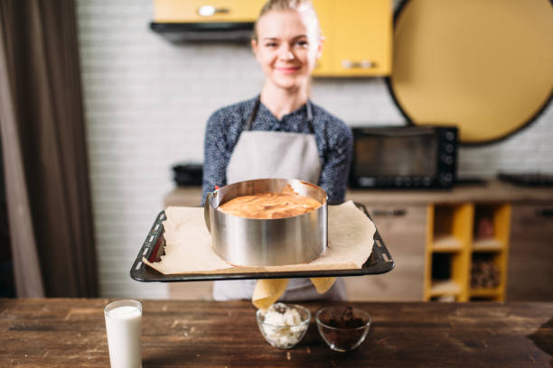 istock Woman cook in apron holds pan with fresh cake 671713054