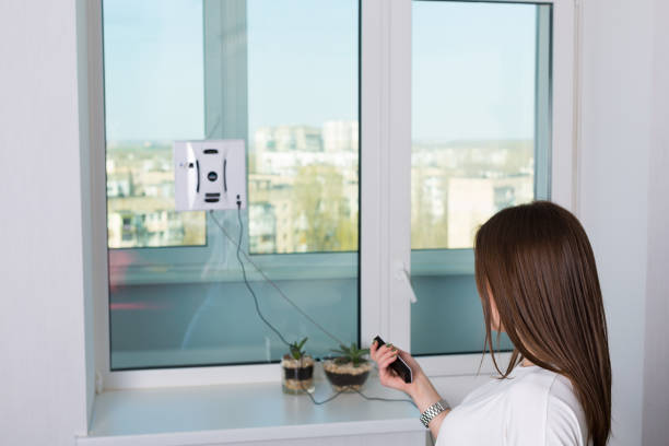 istock Woman cleaning windows with robotic cleaner 671720592
