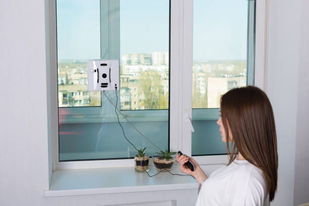 istock Woman cleaning windows with robotic cleaner 671720882