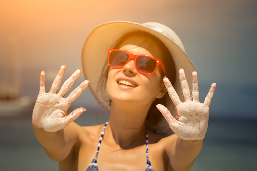 Sun protection cream on female hands. Safe tanning concept.