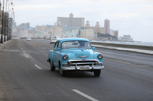 Havana, Cuba-January 28, 2017: One green vintage car is driving on the street along the Malecon in Havana