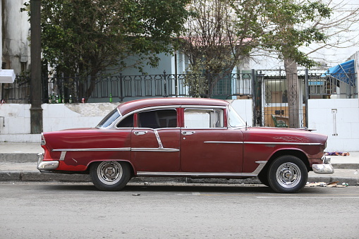 Havana, Cuba-January 28, 2017: One red vintage car park on the street. Residential building on the background.
