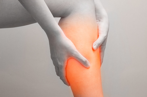 Young woman holding her calf muscle in pain with red highlighted, Isolated on white background