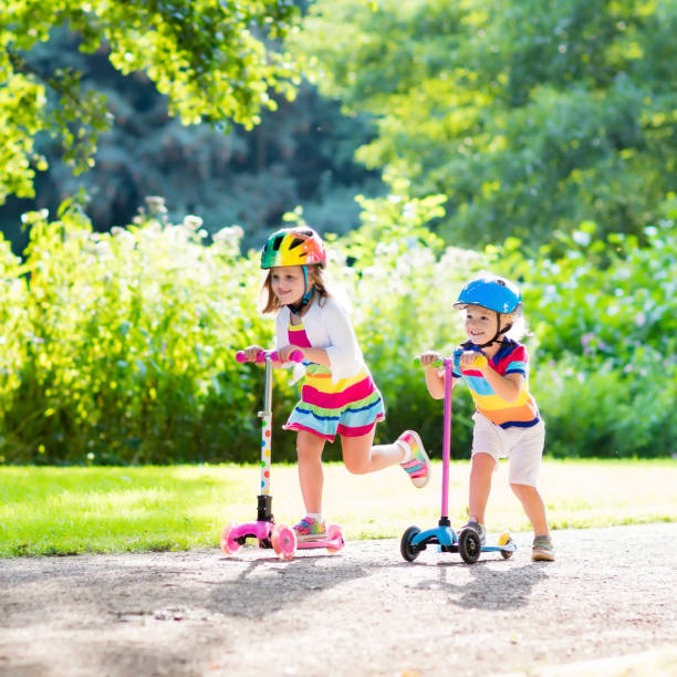istock Kids riding scooter in summer park. 671750908