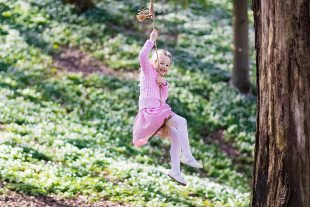 istock Child swinging on tree rope swing 671753756
