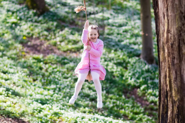 istock Child swinging on tree rope swing 671757374