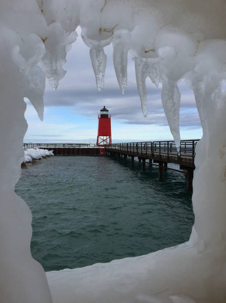 istock Looking at a red lighthouse at the end of a pier through an ice window 671783258