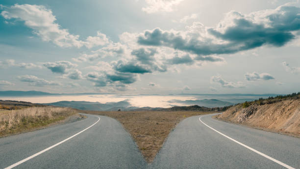 Dilemma with mountain roads spliting in two ways In front of two apparently same roads before the decision which is the right choice. Success concept. forked road photos stock pictures, royalty-free photos & images