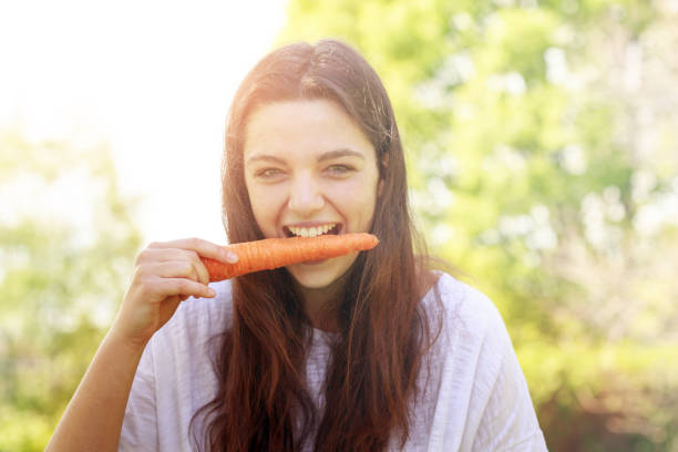 istock woman smiling and eating a carrot 671796910