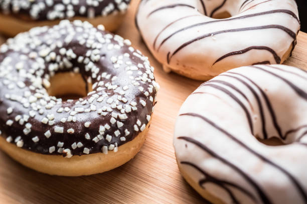 istock Black and white chocolate doughnuts on a wood table 671800048