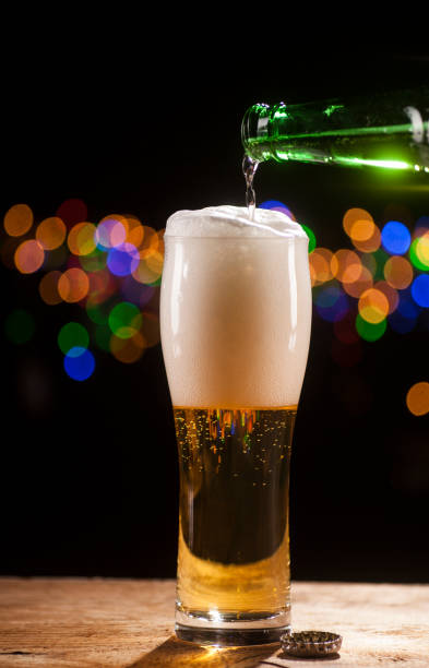 Beer is pouring into glass on bar lights background