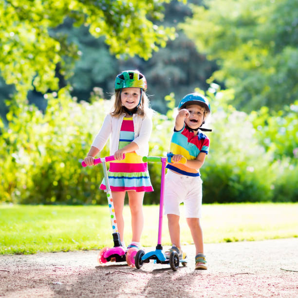 istock Kids riding scooter in summer park. 671823800