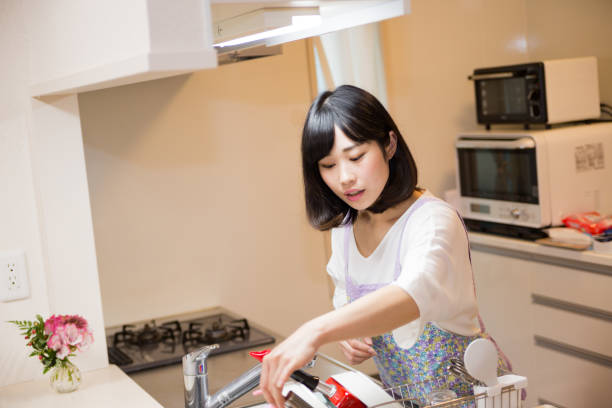istock Japanese woman standing in bright kitchen 671825700