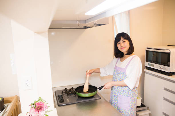 istock Japanese woman standing in bright kitchen 671825898