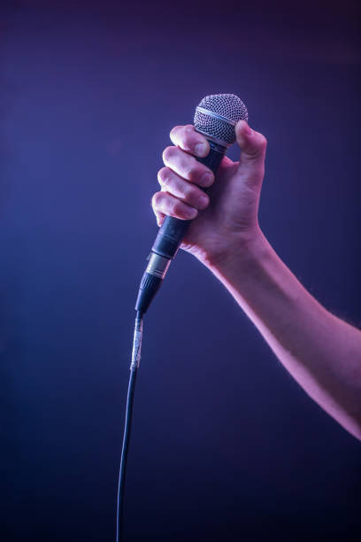 istock hand with microphone on a black background, the music concept, beautiful lighting on the stage 671826092