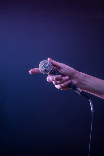 istock hand with microphone on a black background, the music concept, beautiful lighting on the stage 671826096