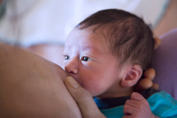 niño recién nacido con grandes ojos marrones mirando a su madre mientras amamanta - human nipple fotos fotografías e imágenes de stock