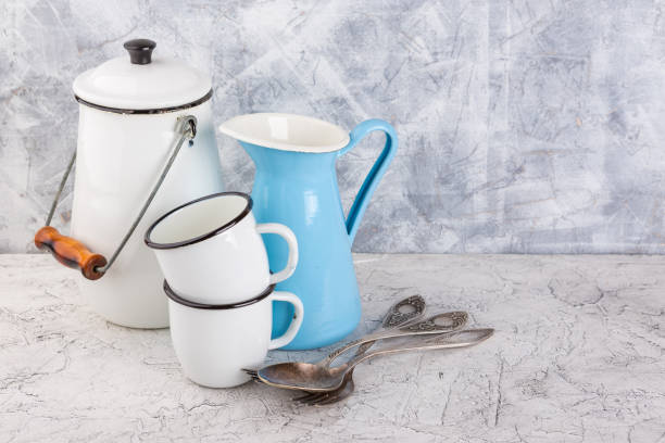 Two white enamel mug, jug blue and white can on light background
