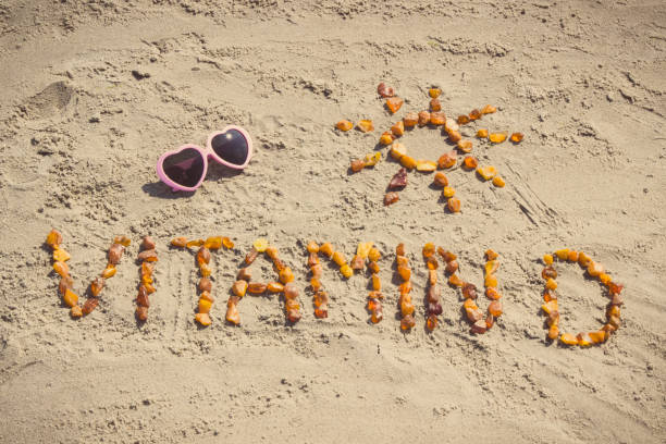Sunglasses, inscription vitamin D and shape of sun on sand at beach, summer time and healthy lifestyle stock photo