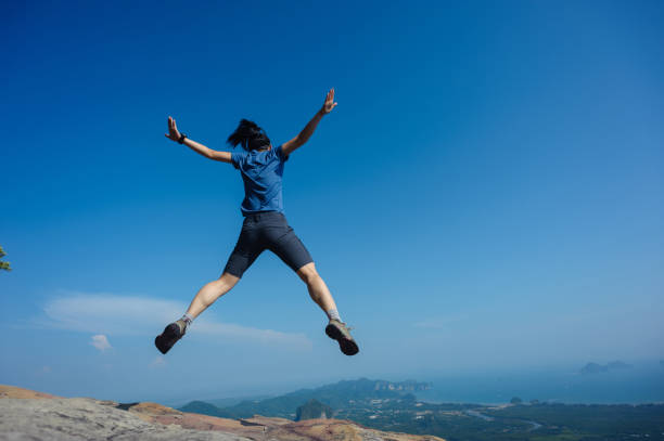 istock jumping on rocky mountain peak, freedom, risk, challenge, success concept 671876590