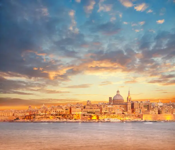Beautiful spires and cathedral dome of Valletta under dramatic sky on the sunset. Valletta, capital of Malta.